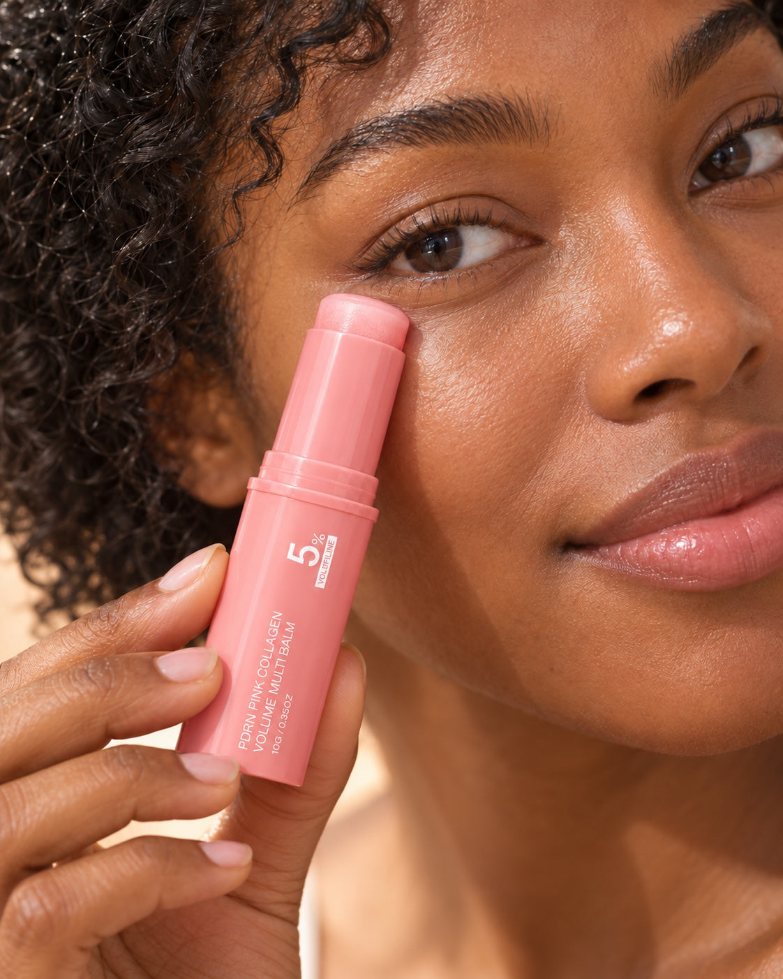 Femme appliquant le stick rose Volume Multi Balm sous l'œil