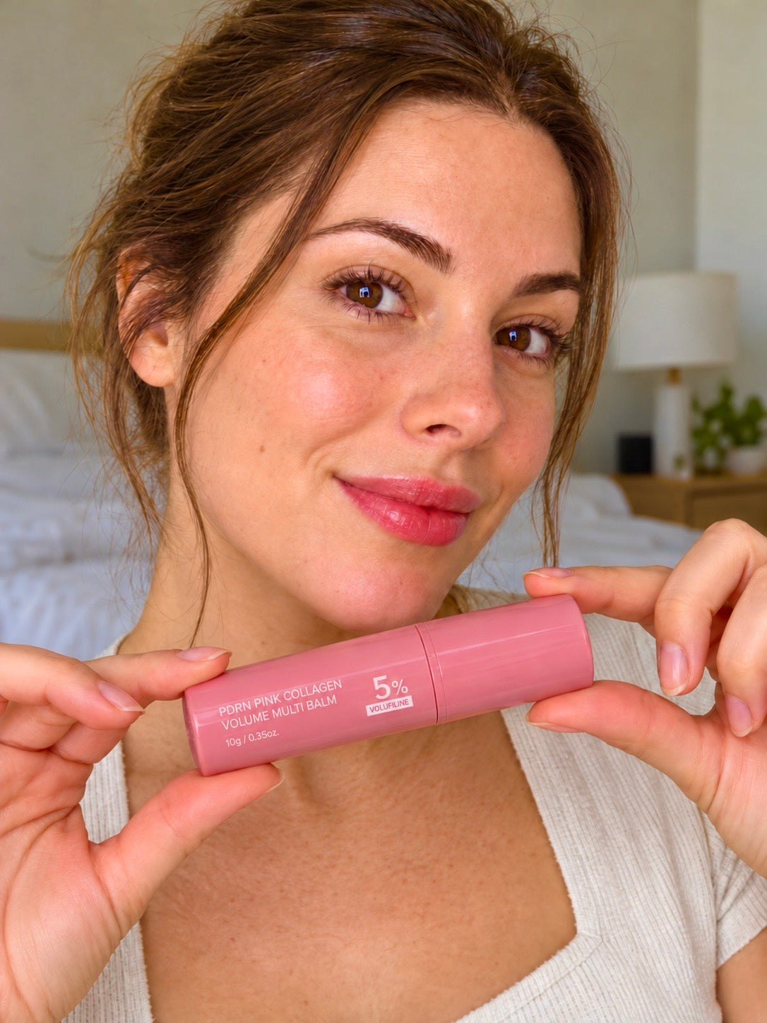 Femme tenant le stick rose Volume Multi Balm fermé, vernis nude – version finale